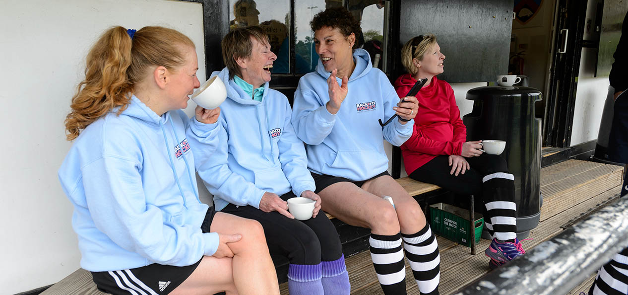 A group of women having a chat during a break in a game of hockey.